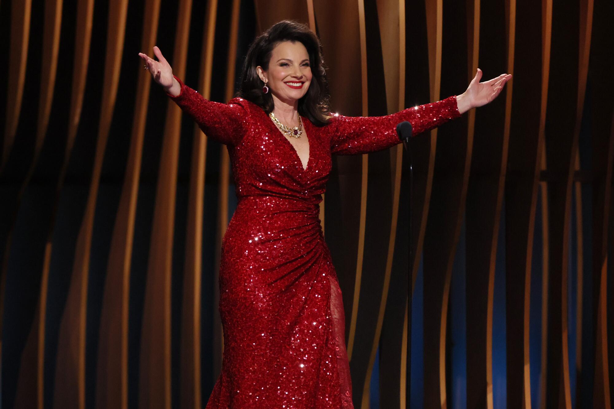 Fran Drescher in a red gown extends her arms toward the audience 