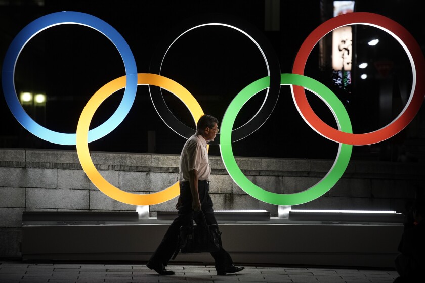 A man walks past the Olympic rings in Tokyo on Tuesday, a year from the start of the 2020 Summer Games.