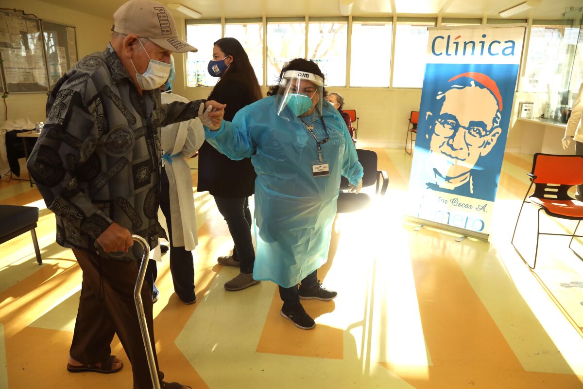 A medical assistant helps an elderly man waiting for a vaccine at Clinica Romero in Los Angeles.