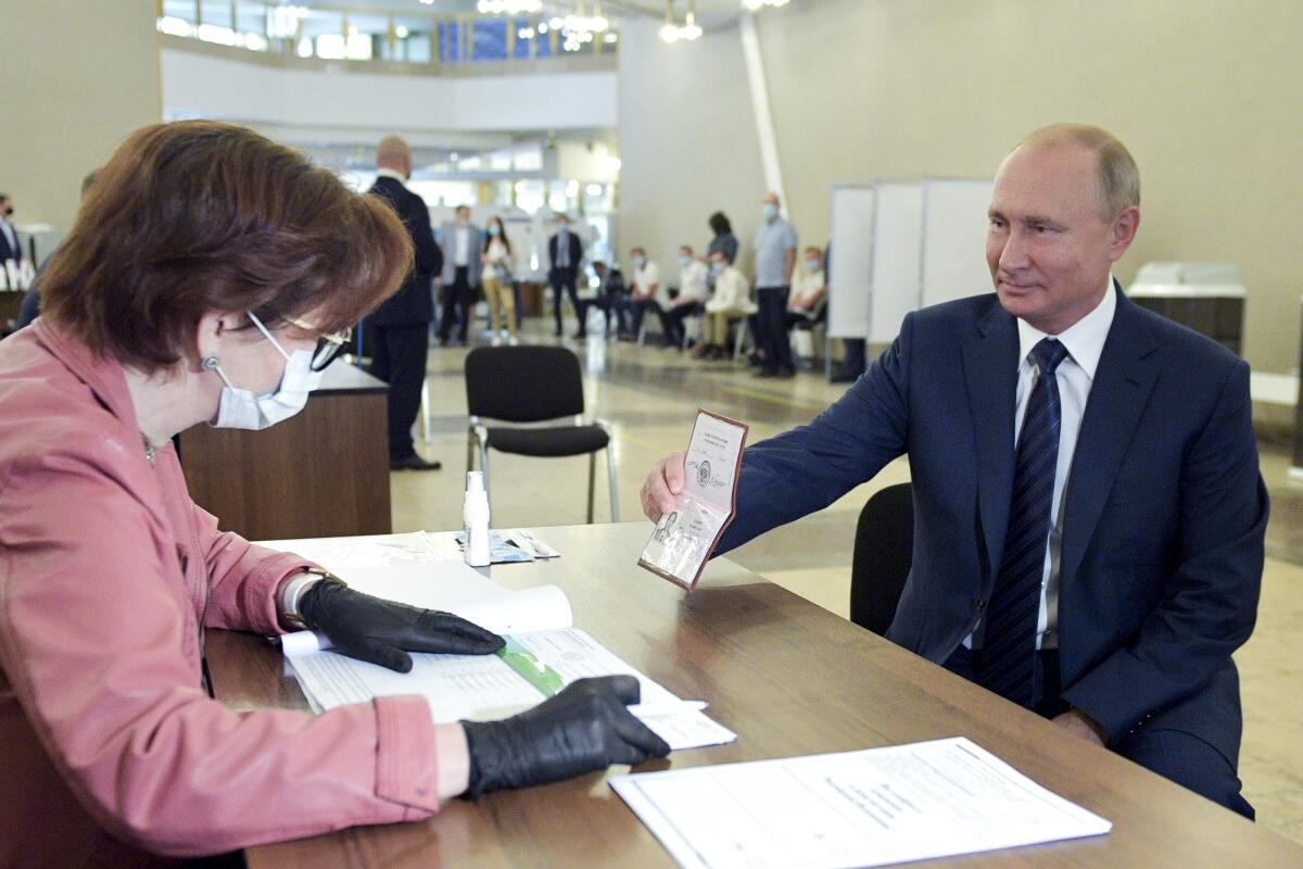 Russian President Vladimir Putin shows his passport as he arrives to vote at a Moscow polling station.