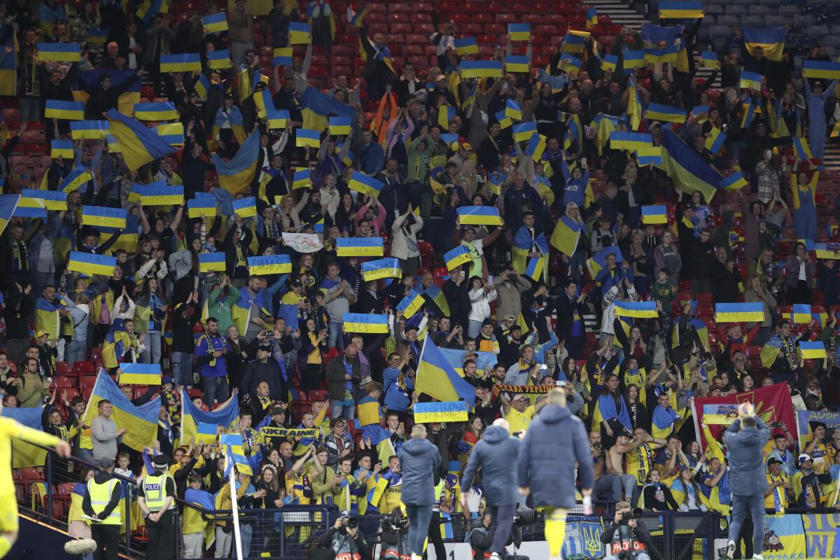 Aficionados de Ucrania sostienen banderas del país al final del partido de la Liga 