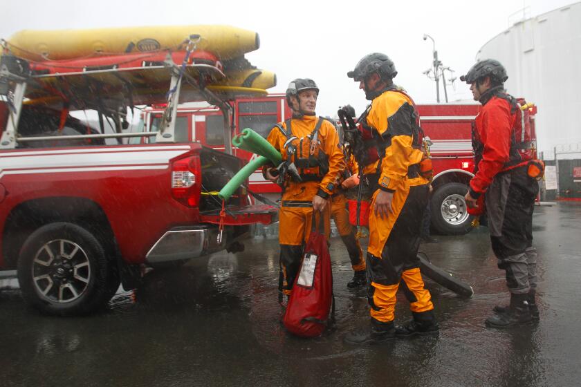 SAN DIEGO, CA - DECEMBER 14: Members of the San Diego Lifeguard River Rescue Team converge after rescuing a man and woman in a flood control channel along I-15 in Mission Valley during a storm on Tuesday, Dec. 14, 2021 in San Diego. The man and woman were rescued in the channel filled with fast moving water after they fell in trying to rescue their dog. (K.C. Alfred / The San Diego Union-Tribune)