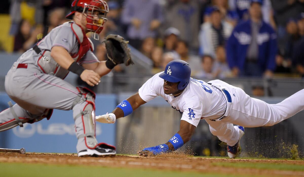 Los Angeles Dodgers' Yasiel Puig, right, scores as Cincinnati Reds catcher Tucker Barnhart waits for the throw after Howie Kendrick made it to first on an error by Reds first baseman Joey Votto during the sixth inning on Tuesday.