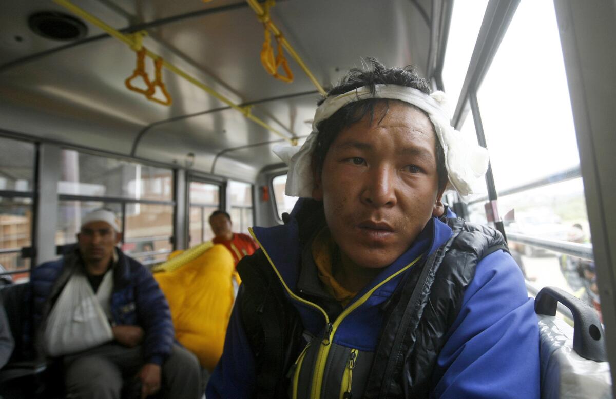 Injured Nepalese guides sit in a bus after they were evacuated from the main base camp on Mt. Everest on Sunday.