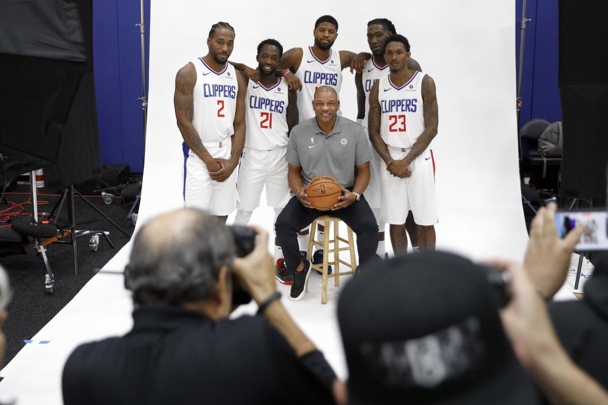 Clippers players (from left) Kawhi Leonard, Patrick Beverley, Paul George, Montrezl Harrell and Lou Williams pose for photos with coach Doc Rivers during media day Sunday.
