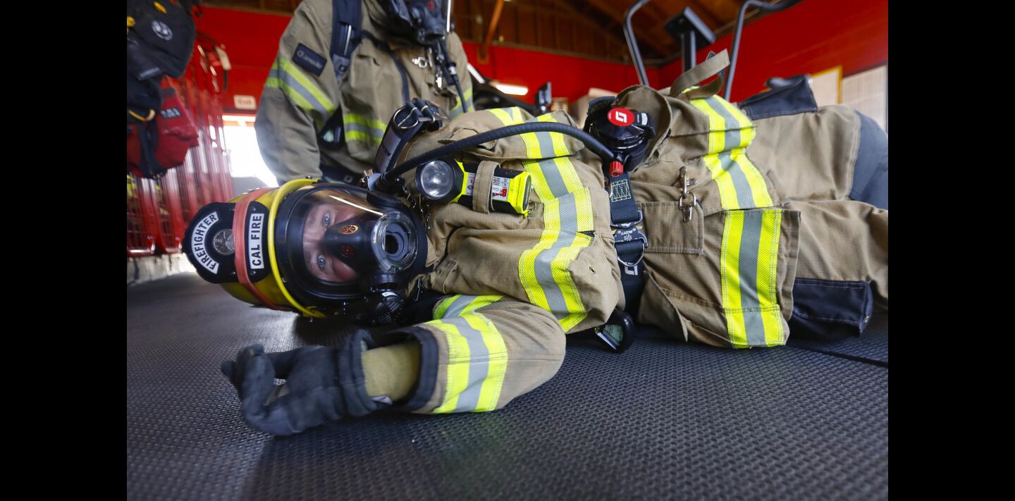 Cal Fire firefighter Trent Grinstead trains on a new style of a self-contained breathing apparatus (SCBA) which includes crawling on the ground and rolling over to simulate maneuvering through low-lying obstructions in a fire.