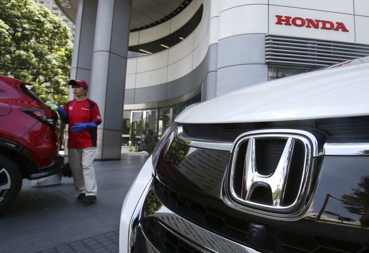 FILE - An employee of Honda Motor Co. cleans a Honda car displayed at its headquarters in Tokyo on July 31, 2018. Honda’s fiscal first quarter profit fell 33% from 2021 as a global computer chip shortage, a pandemic-related lockdown in China and the rising costs of raw materials hurt the Japanese automaker. Tokyo-based Honda Motor Co. reported Wednesday, Aug. 10, 2022, that its profit totaled 149.2 billion yen ($1.1 billion) in the April-June quarter, down from 222.5 billion yen ($1.7 billion) a year earlier. Quarterly sales slipped 7% to 3.8 trillion yen ($28 billion). (AP Photo/Koji Sasahara, File)