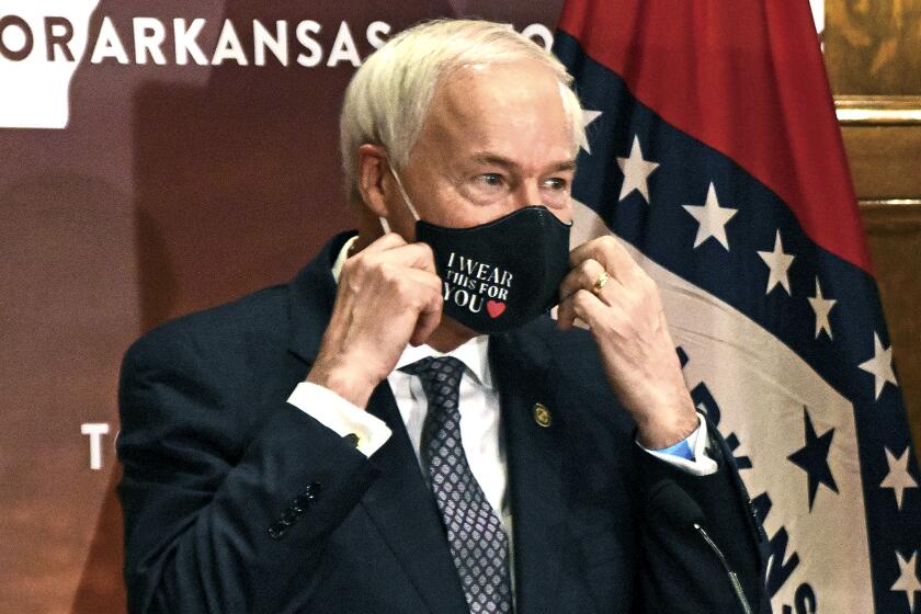 FILE - In this July 20, 2020 file photo, Arkansas Gov. Asa Hutchinson removes his mask before a briefing at the state capitol in Little Rock. Hutchinson has signed into law a measure that would allow doctors to refuse to treat someone because of moral or religious objections. Gov. Hutchinson on Friday, March 26, 2021, signed the legislation, despite objections that it would give medical providers broad powers to turn away LGBTQ patients and others. (Staci Vandagriff/The Arkansas Democrat-Gazette via AP, File)