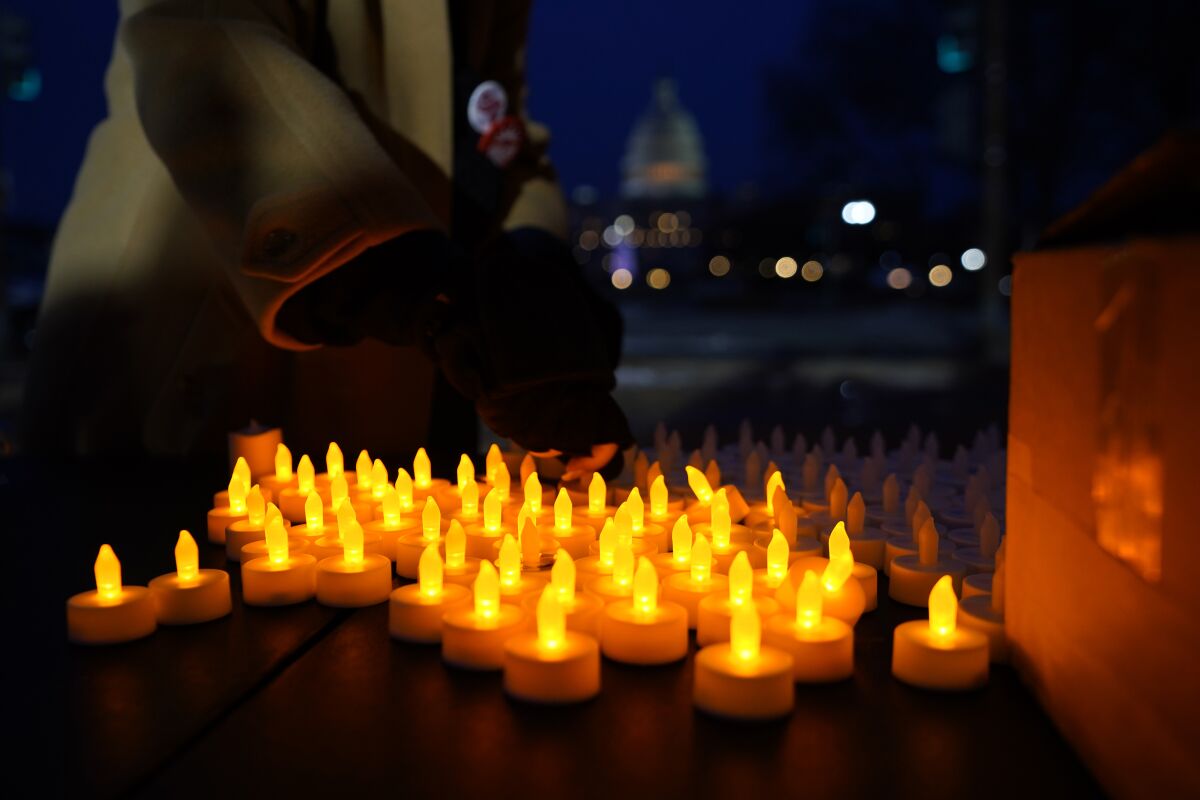 With the U.S. Capitol building in the background, a person turns flameless candles on so that they can be distributed at a vigil Thursday, Jan. 6, 2022, in Washington, on the one year anniversary of the attack on the U.S. Capitol. (AP Photo/Julio Cortez)