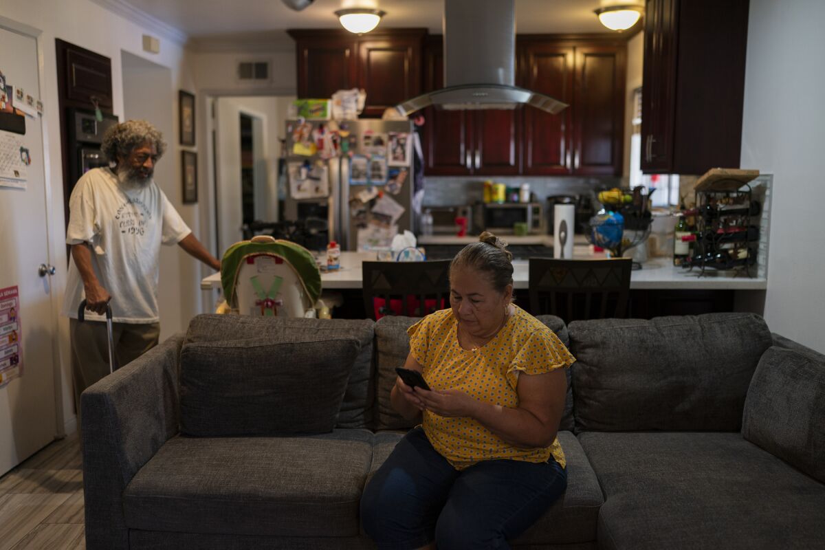 Ana Sandoval, mother of Eyvin Hernandez checks her phone while talking with Hernandez's step-father, Pedro Martinez,
