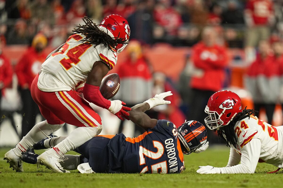 Denver Broncos running back Melvin Gordon III (25) loses a fumble after being hit by Kansas City Chiefs linebacker Melvin Ingram, right, before outside linebacker Nick Bolton (54) returned it for a touchdown during the second half of an NFL football game Saturday, Jan. 8, 2022, in Denver. (AP Photo/Jack Dempsey)