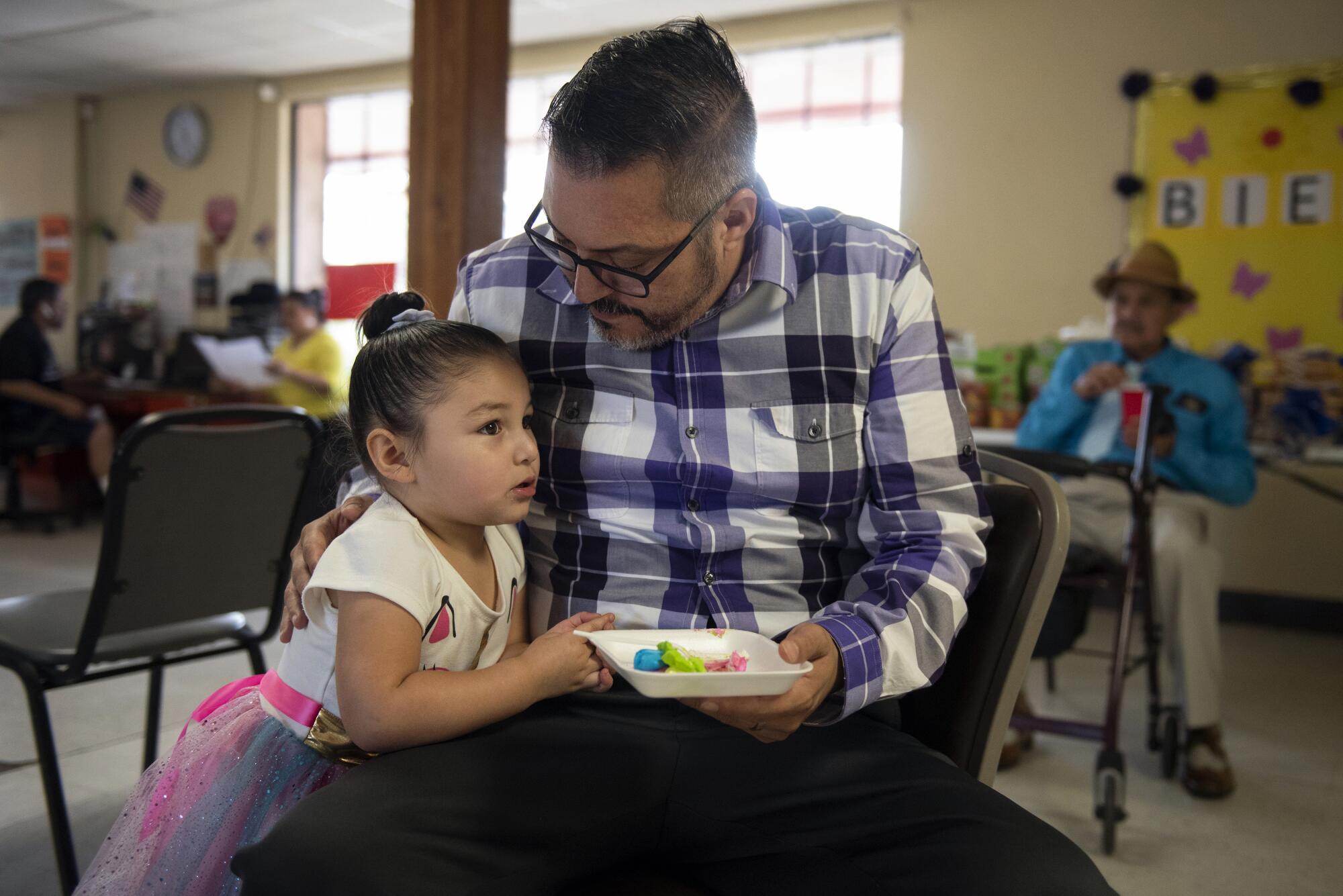 Mike Smith eats cake with his daughter, Eva, 3, after a service at the Holding Institute, a community center he oversees.