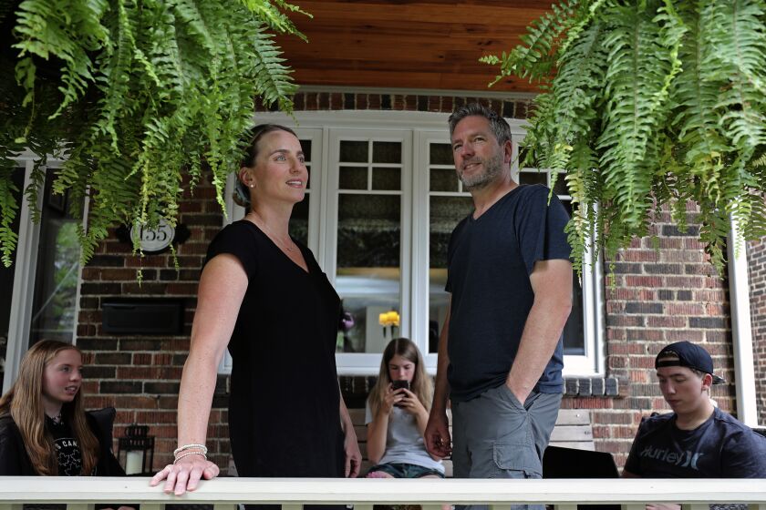 Amanda and David Wood stand as their children, twins Ruby and Lola, and Ethan sit on the porch of their family home in Toronto, Canada, on Monday, July 12, 2021. When Amanda heard that hundreds of coronavirus shots were available for teens, only one thing prevented her from racing to the vaccination site at a Toronto high school - her 13-year-old daughter’s fear of needles. (AP Photo/Kamran Jebreili)