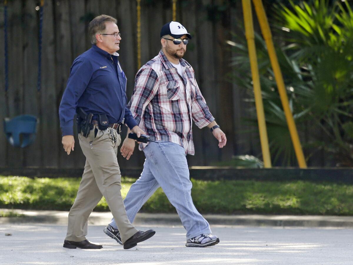 George Zimmerman, right, is escorted to a home by a police officer Monday in Lake Mary, Fla., after a domestic incident involving his wife, Shellie.