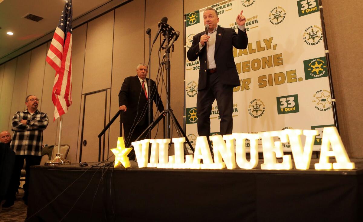 Sheriff Alex Villanueva speaking into a microphone on a stage