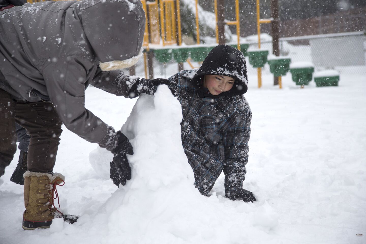 Jessica Pompa and Albert Arroyo make a snowman at Firehouse Park in Running Springs.