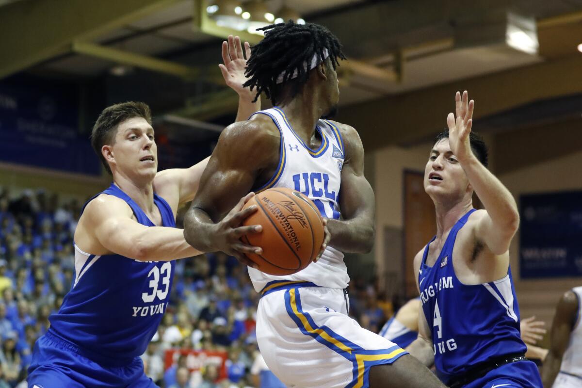 UCLA forward Jalen Hill (24) is double teamed by BYU forward Dalton Nixon (33) and guard Alex Barcello (4) during a game Nov. 25 in Lahaina, Hawaii.