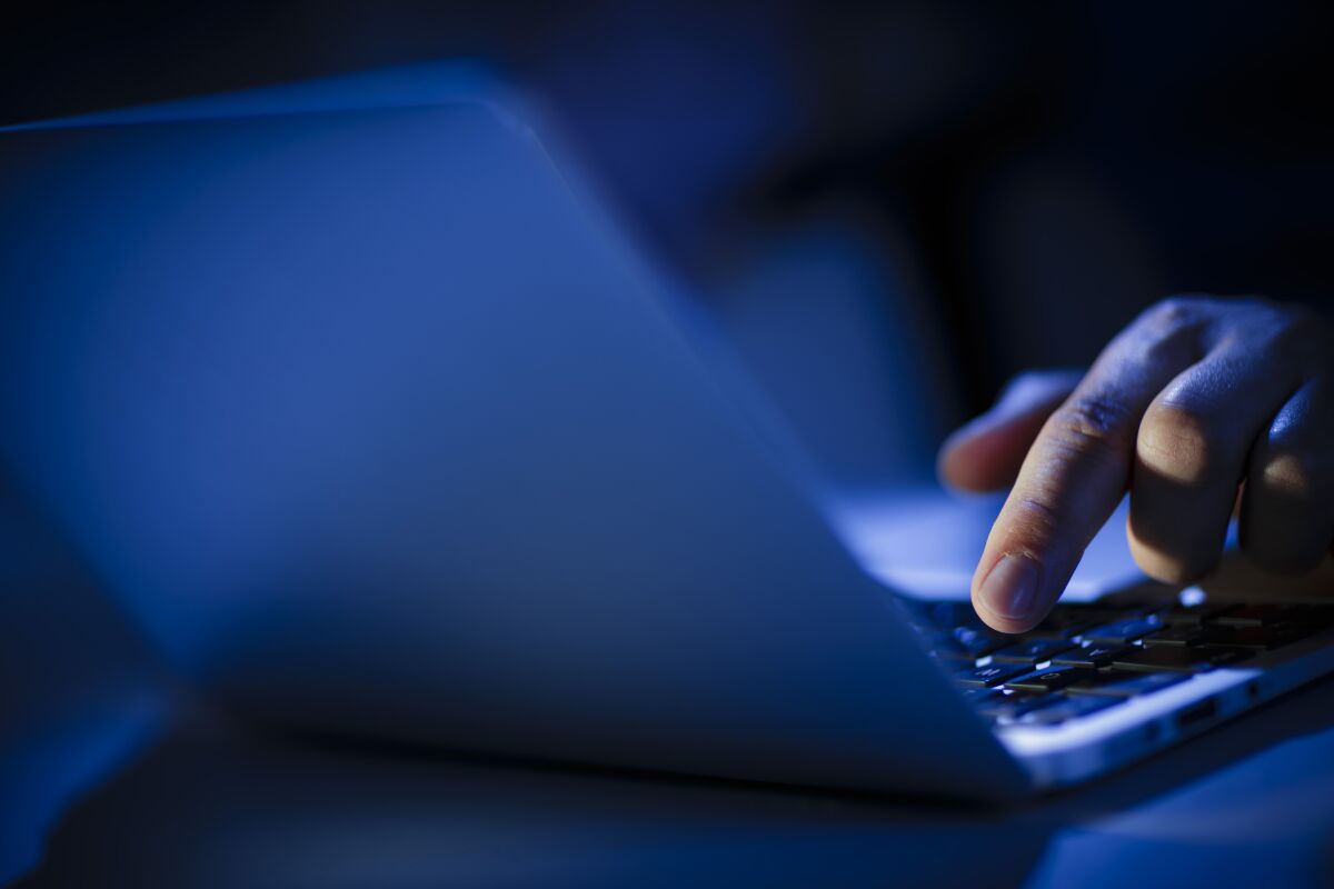 In a photo illustration, hands type on a computer keyboard
