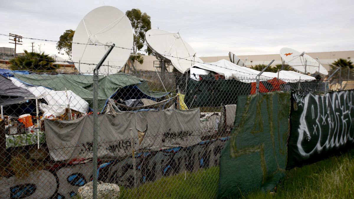 A homeless encampment sits between large satellite dishes and a wash in Chatsworth on March 1, 2019.