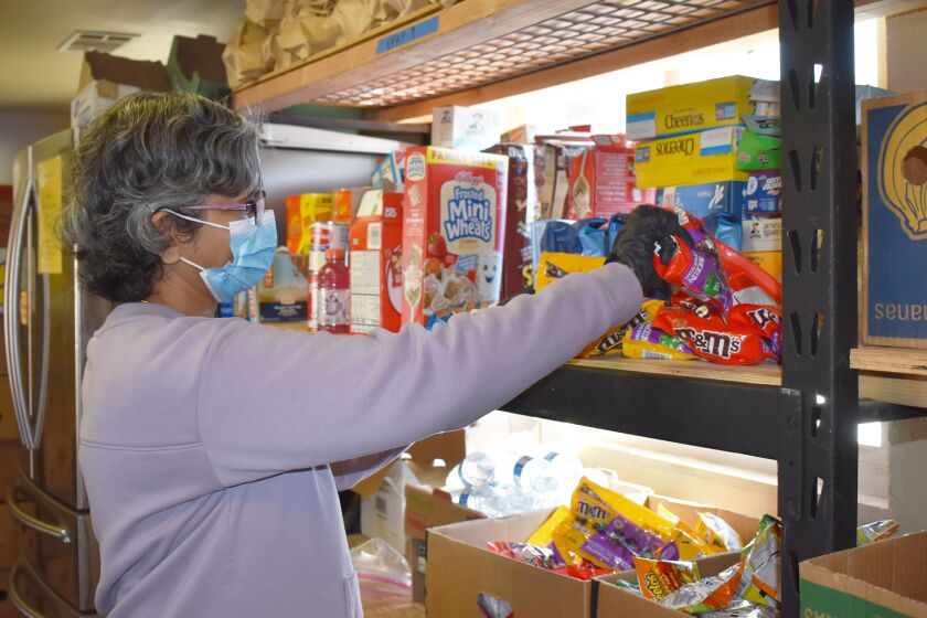 Volunteer Lakshmi Mullaguru selects donated food items to place in a pantry box at The Community Food Connection in Poway.