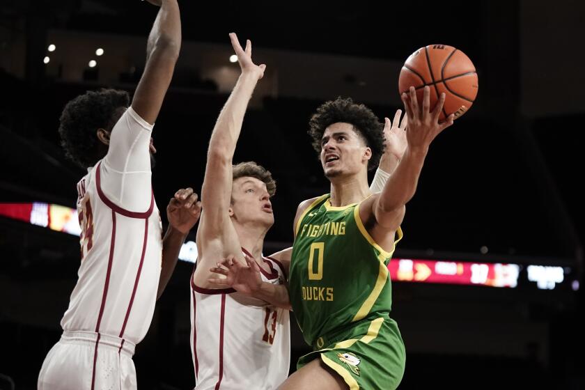Oregon's Will Richardson drives against USC's Drew Peterson, middle, and Joshua Morgan, left, on Jan. 15, 2022.