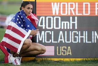Sydney McLaughlin poses by a sign after winning the  women's 400-meter hurdles at the 2022 World Athletics Championships.