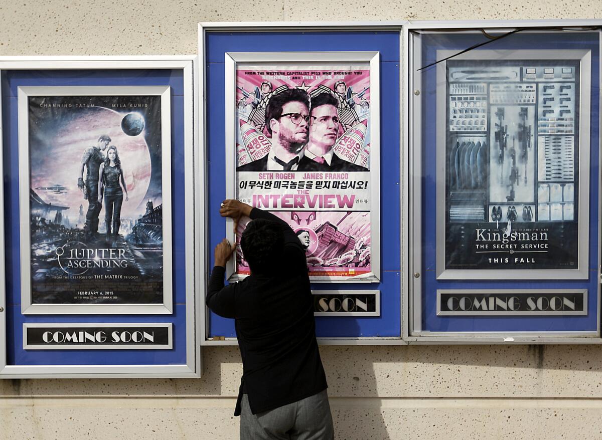 In this photo from Dec. 17, a worker removes poster for the movie "The Interview" from a display case at a Carmike Cinemas in Atlanta. A number of smaller theaters and chains said Tuesday that they would begin showing the film Christmas Day, putting the comedy back in theaters after Sony Pictures Entertainment canceled its release.