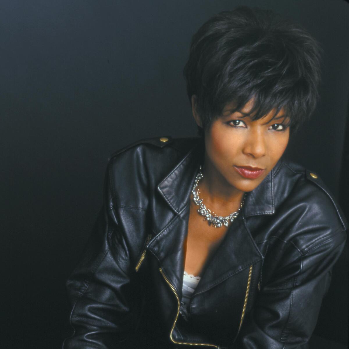 A woman in a black leather jacket sits for a portrait.