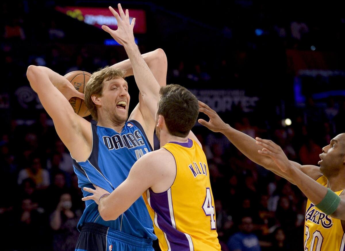 Mavericks power forward Dirk Nowitzki is pressured by Lakers forward Ryan Kelly (4) and guard Jodie Meeks (20) in the first half.