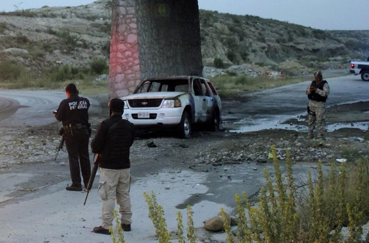 Mexican policemen inspect the site where they reported finding the bodies of five charred people on July 18. The state of Coahuila, where this incident took place, has had 18 people slain in recent days.