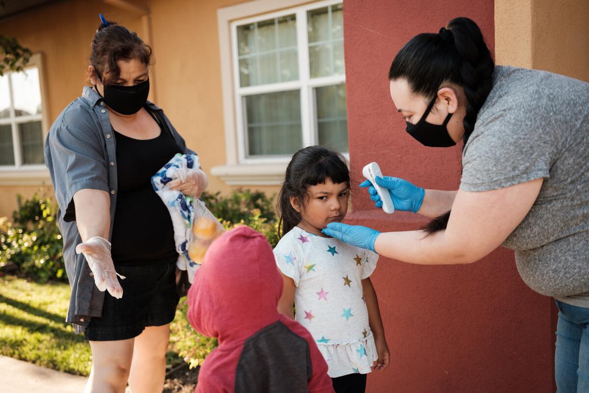 A child's temperature is taken at Head Start day care center for the children of farmworkers in Stockton on July 22.