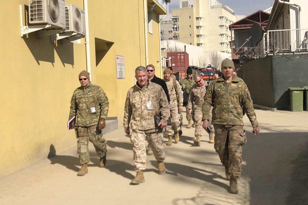 A group of men in military fatigues walk down a street