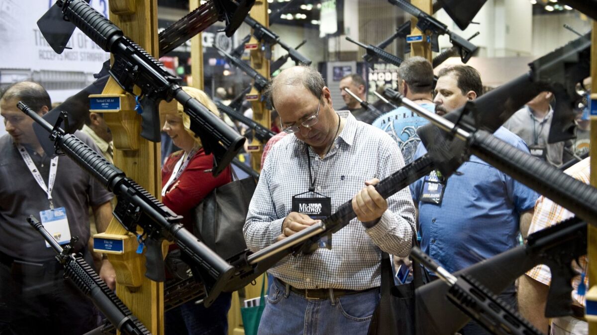 A man examines a weapon at the National Rifle Assn.'s annual meeting in Indianapolis in 2014. A new study finds that gun injuries drop 20% while the NRA is holding its convention.