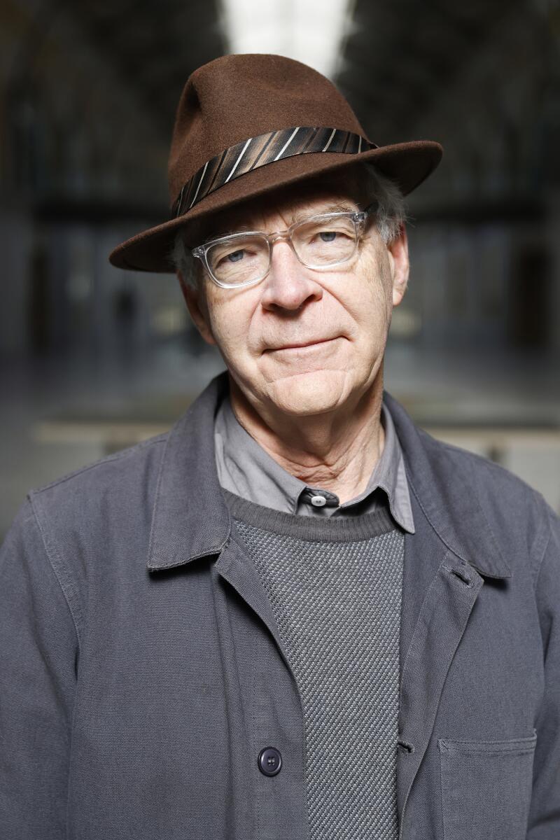 A man in a brown hat with a gray jacket over a gray sweater and collared shirt.