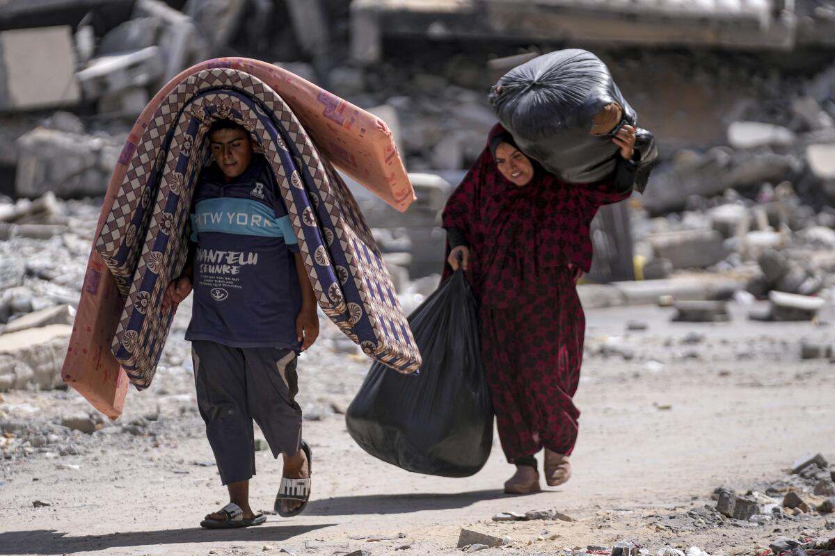 Palestinians displaced by the Israeli air and ground offensive on the Gaza Strip flee from Hamad City carrying possessions.