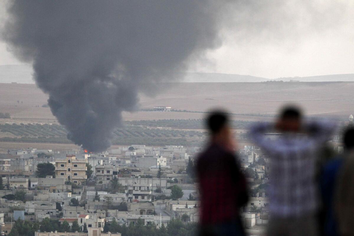 Smoke rises in the Syrian town of Kobani as Turkish Kurds watch across the border in the town of Suruc, Turkey.
