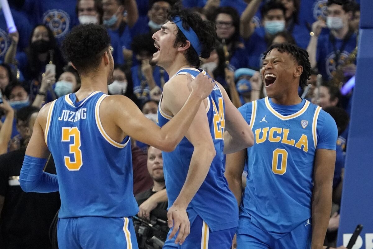 UCLA guard Jaime Jaquez Jr., center, celebrates as time runs out with guard Johnny Juzang, left, and guard Jaylen Clark in second half of an NCAA college basketball game against Southern California Saturday, March 5, 2022, in Los Angeles. UCLA won 75-68. (AP Photo/Mark J. Terrill)