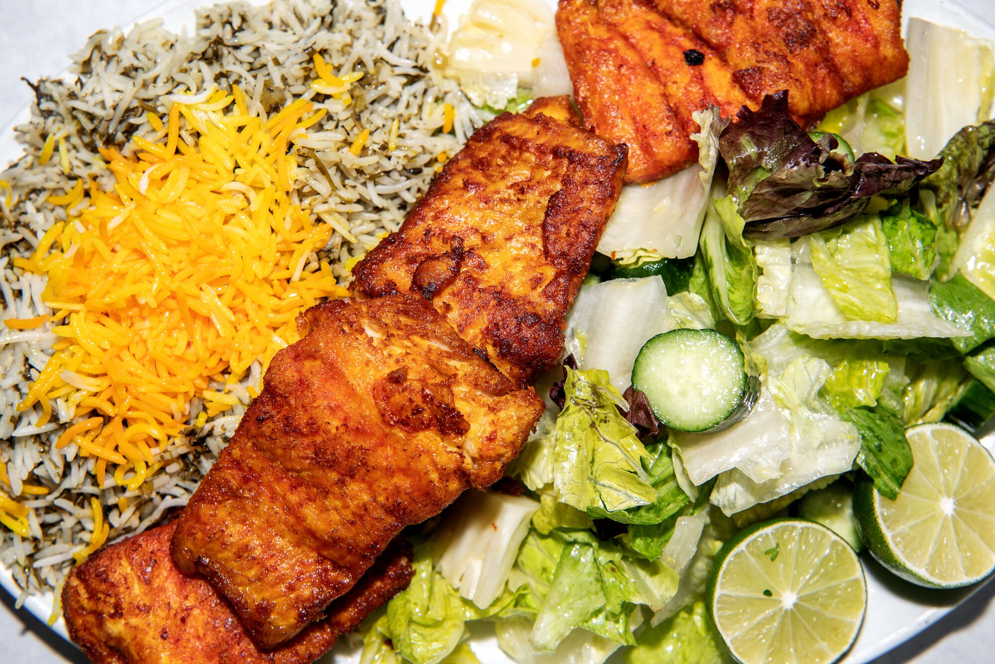 Overhead view of fried white fish with rice and salad from Darya