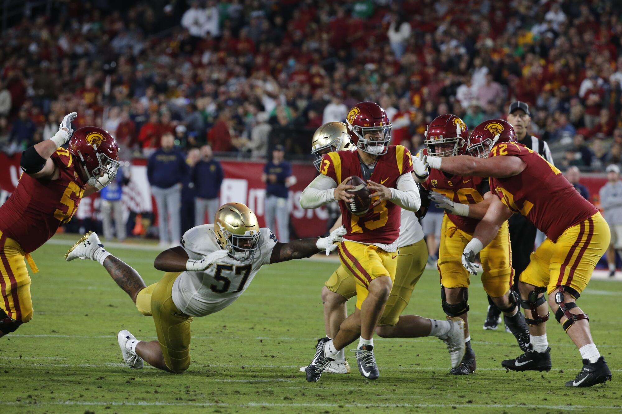 USC quarterback Caleb Williams runs past Notre Dame defensive tackle Jayson Ademilola 