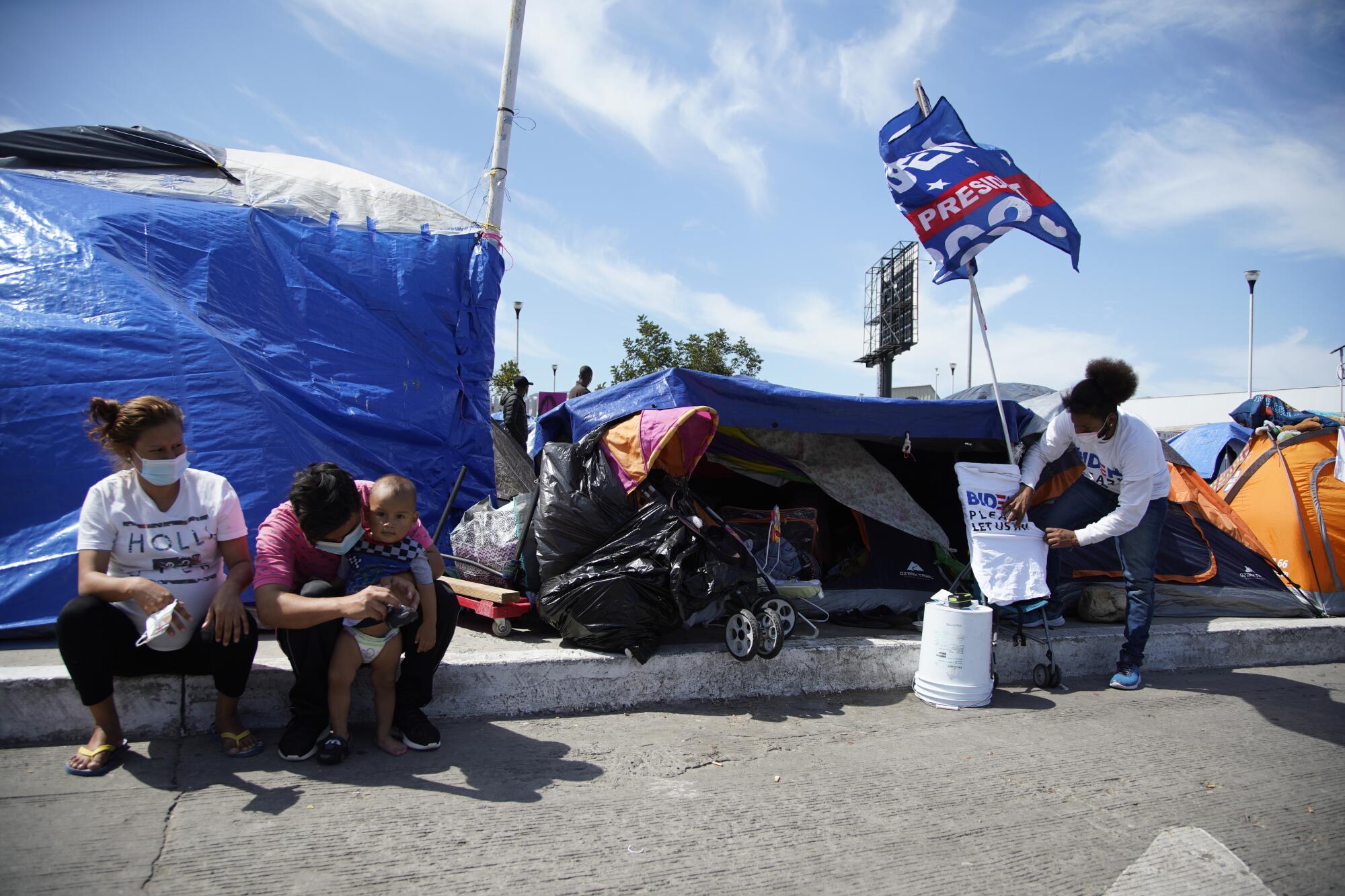 People sit or stand in a tent camp in Tijuana.