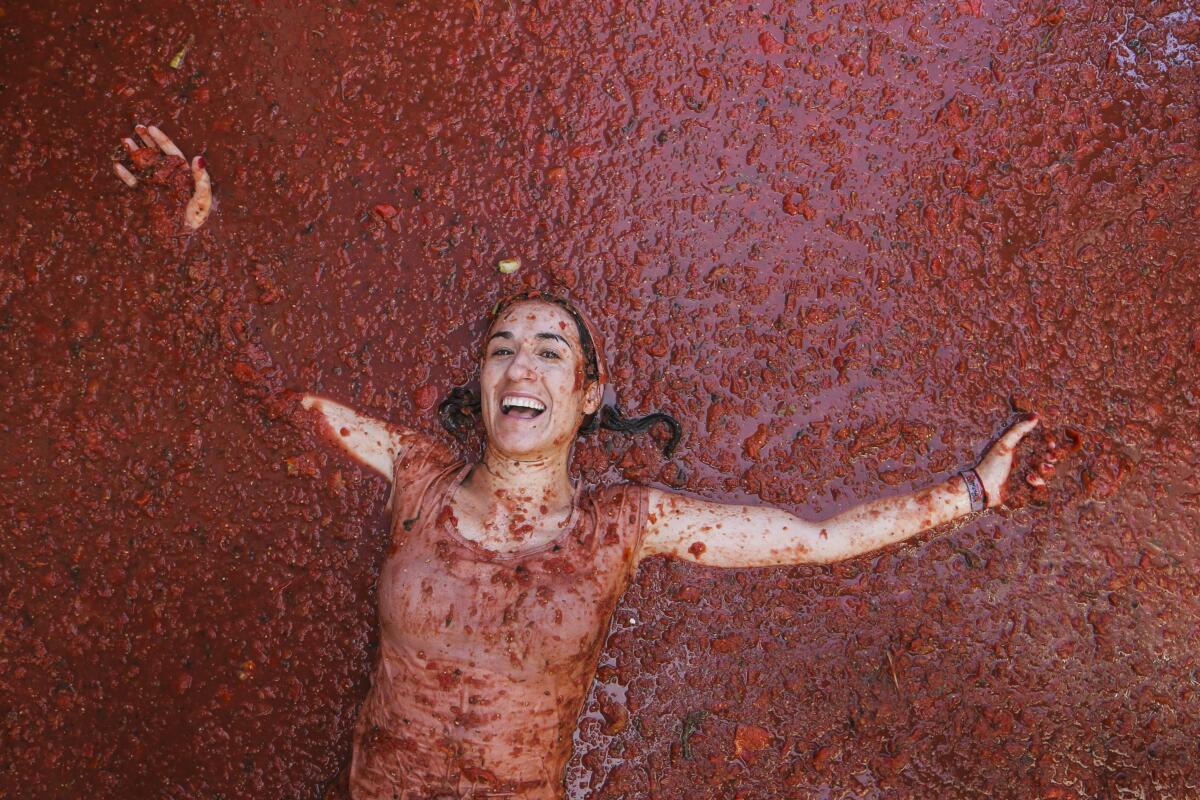 Una participante nada en una calle inundada de tomates aplastados tras la "Tomatina"