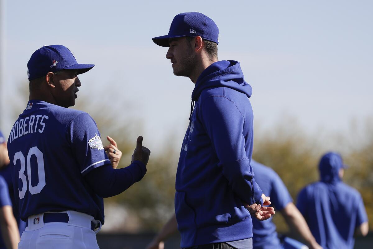 Dodgers manager Dave Roberts, left, talks with center fielder Cody Bellinger at spring training in Glendale, Ariz. 
