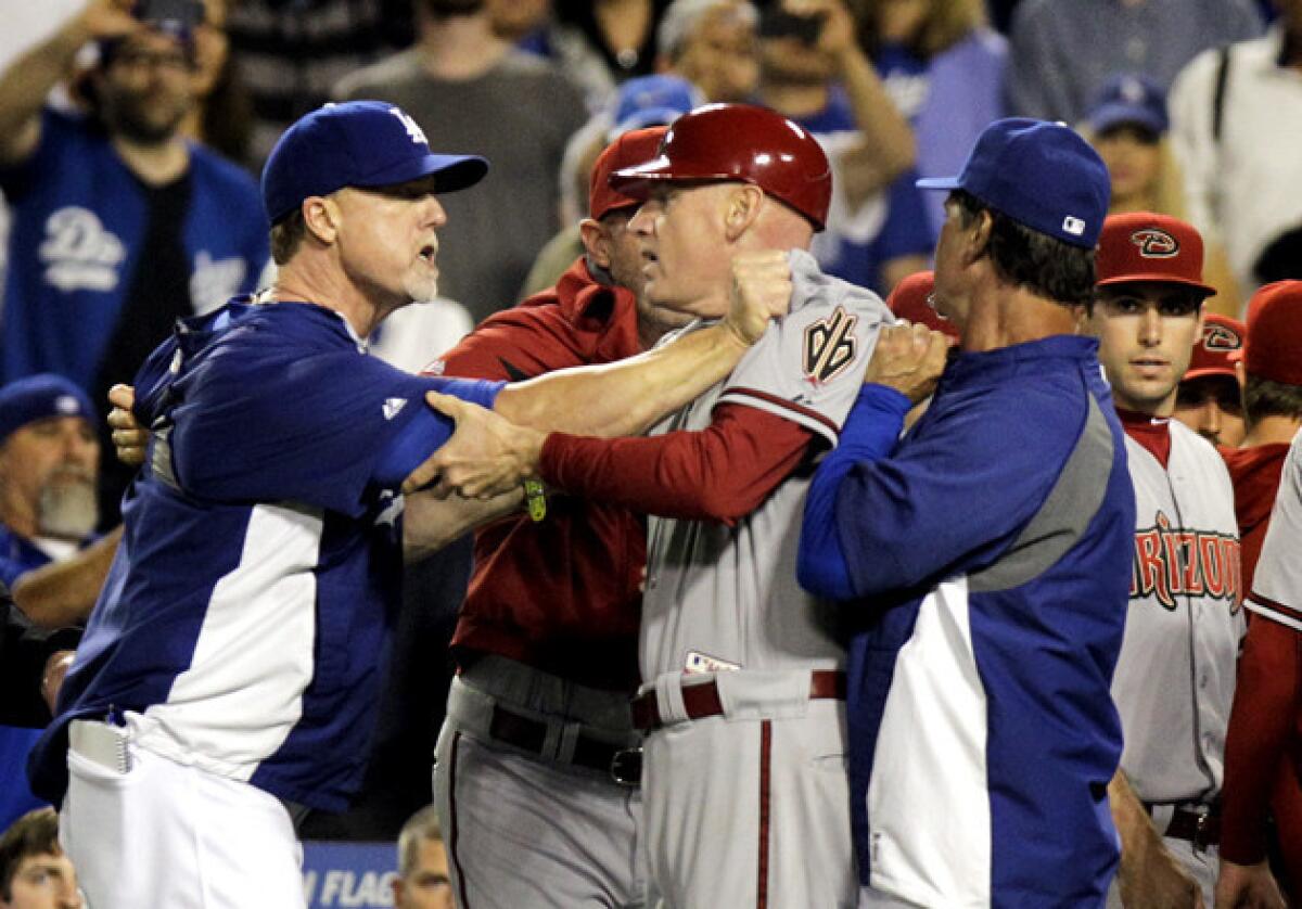 Dodgers hitting coach Mark McGwire, left, and Dodgers Manager Don Mattingly grab onto Arizona Diamondbacks third base coach Matt Williams after Dodgers starting pitcher Zack Greinke was hit by a pitch and both benches cleared.