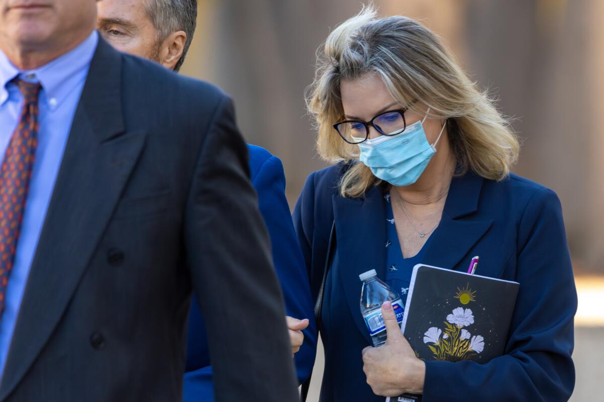 A woman in a surgical mask walks with two men.