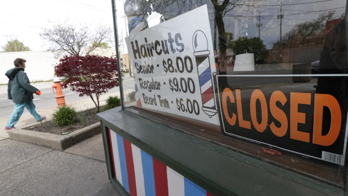 A barbershop with signs in its window showing the price of haircuts and that the business is closed