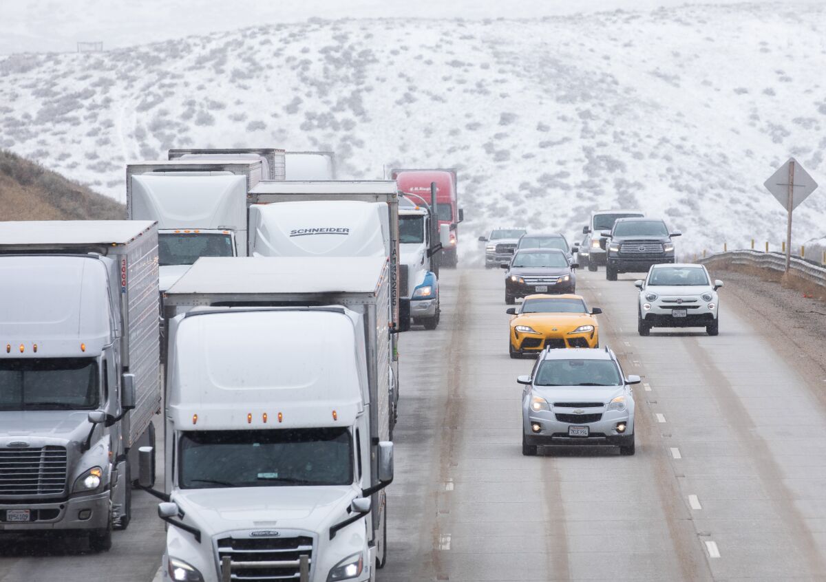 Traffic on the 5 Freeway travels through a snowy landscape.