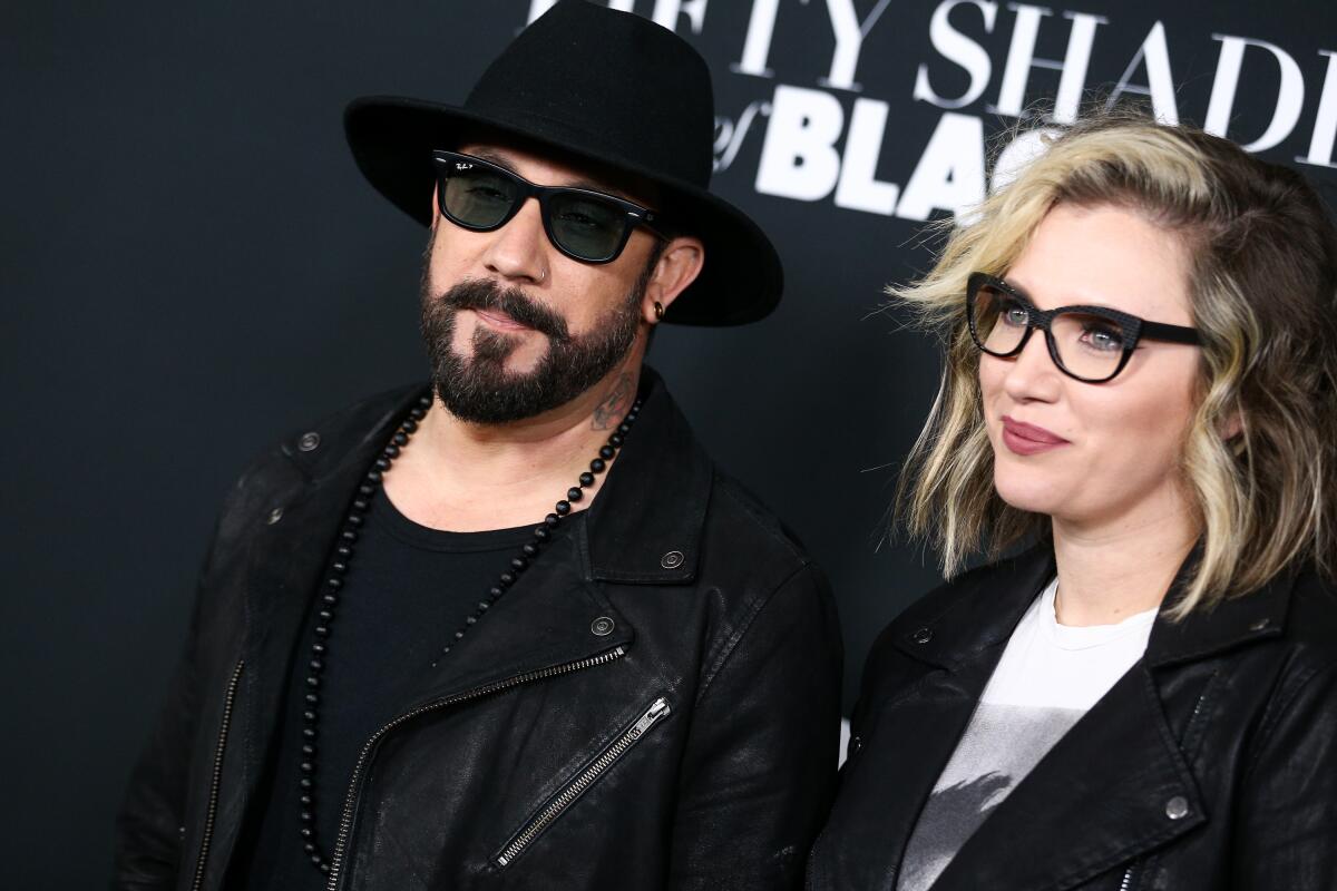 A.J. McLean wears all black and dark sunglasses as he poses with wife Rochelle McLean at a premiere