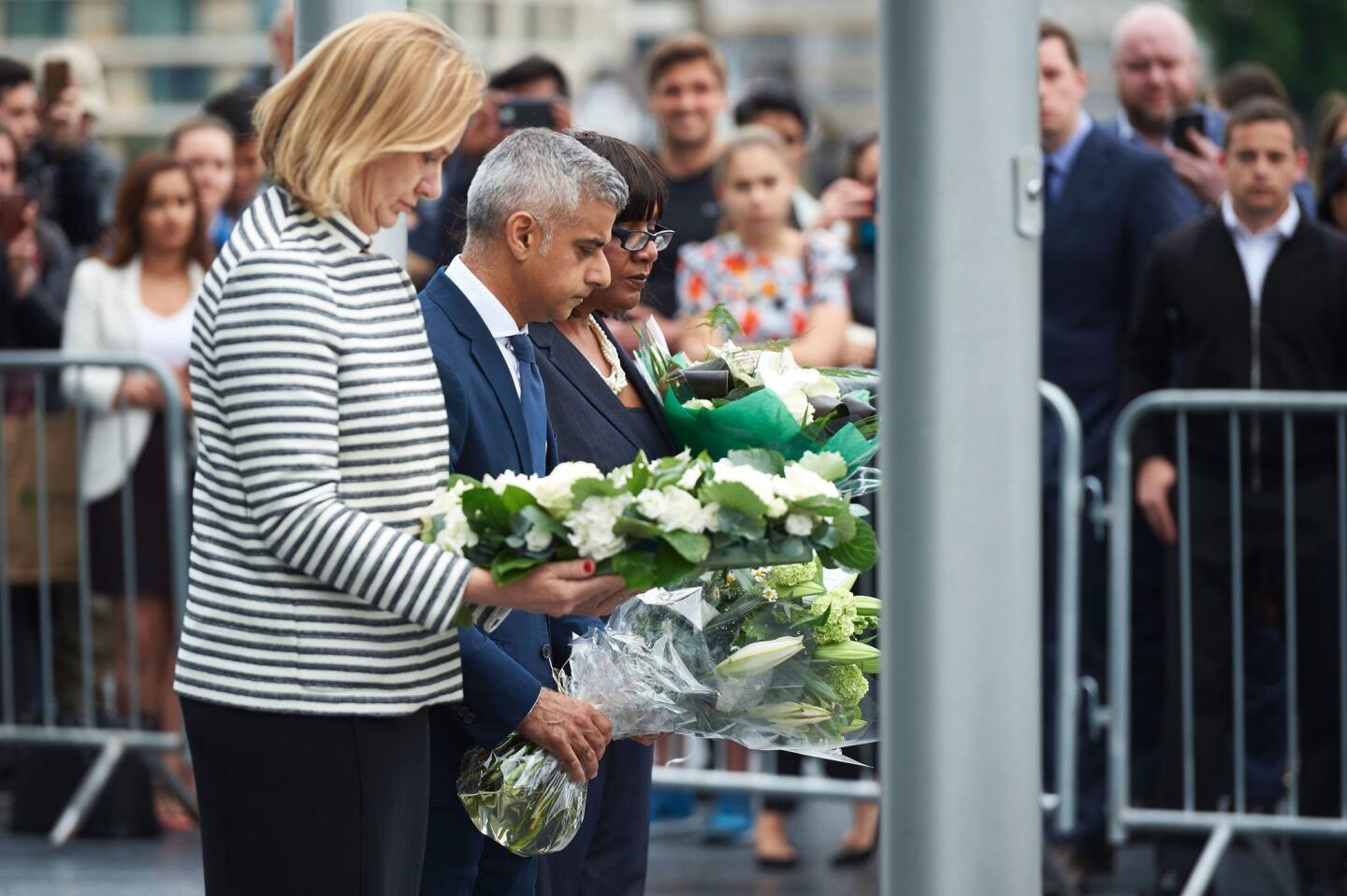 From left: London Home Secretary Amber Rudd, Mayor Sadiq Khan and Shadow Home Secretary Diane Abbott hold flowers at Potters Fields Park in London on June 5, 2017, during a vigil to commemorate the victims of the terror attack on London Bridge and at Borough Market.