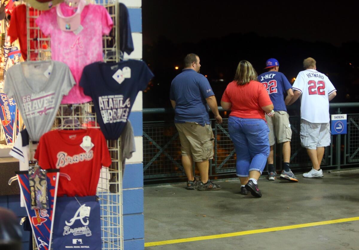 Baseball fans look over a railing at Turner Field near the scene where a man fell about 65 feet to his death Monday night.