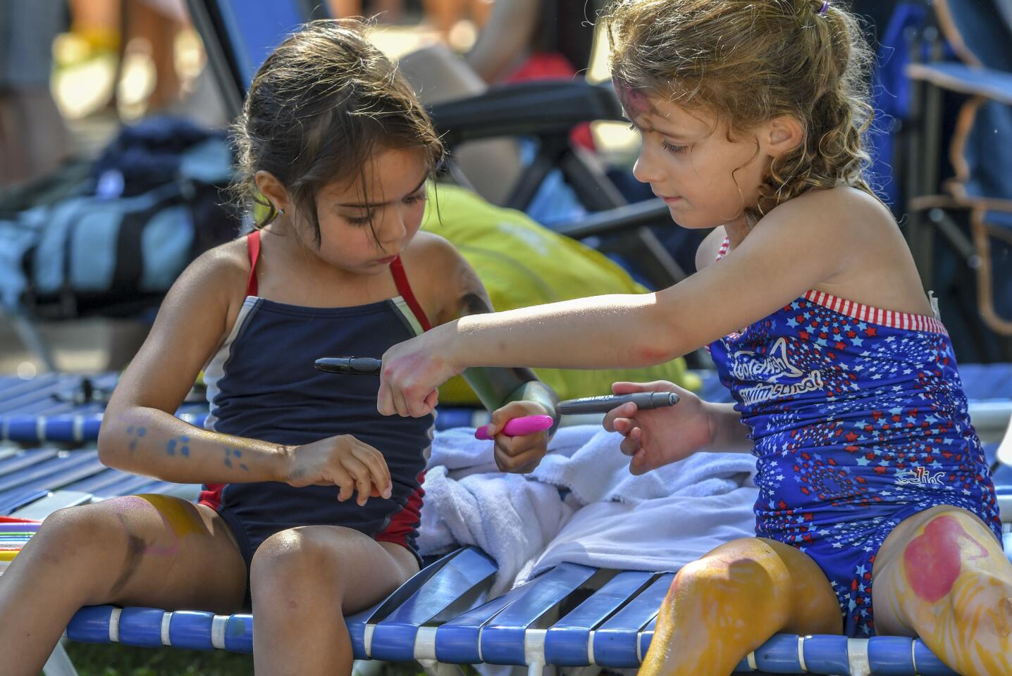 Harper Choice swimmers Ava Portz (L) and Caroline Tiplitz exchange markers as they color themselves during a break at the Columbia Neighborhood Swim League meet between host Clemens Crossing and Harper's Choice Saturday morning in Columbia.
